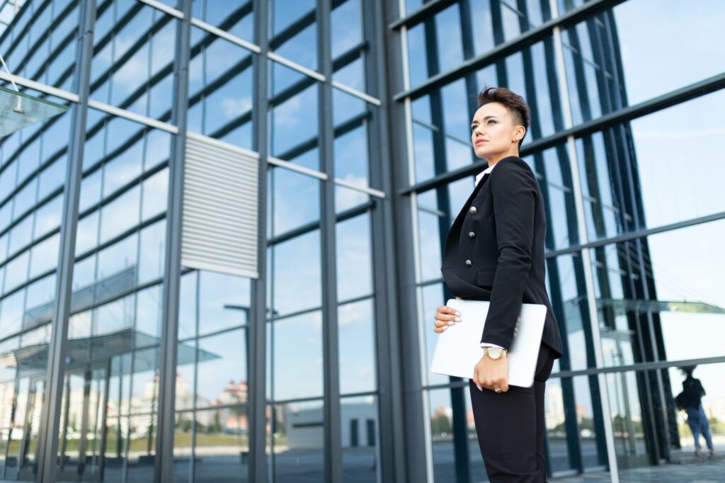classic style boss stands with papers at the facade of a modern glazed business center building