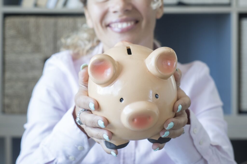 Hands of happy woman showing piggy bank to save money. Concept of saving money